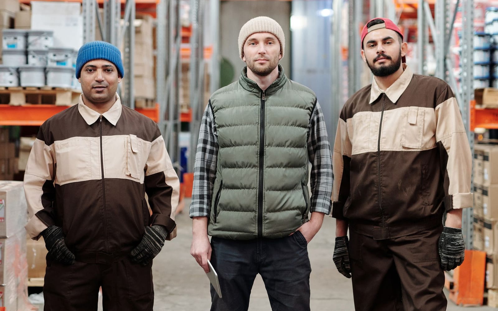 Three warehouse workers in work clothes at their company