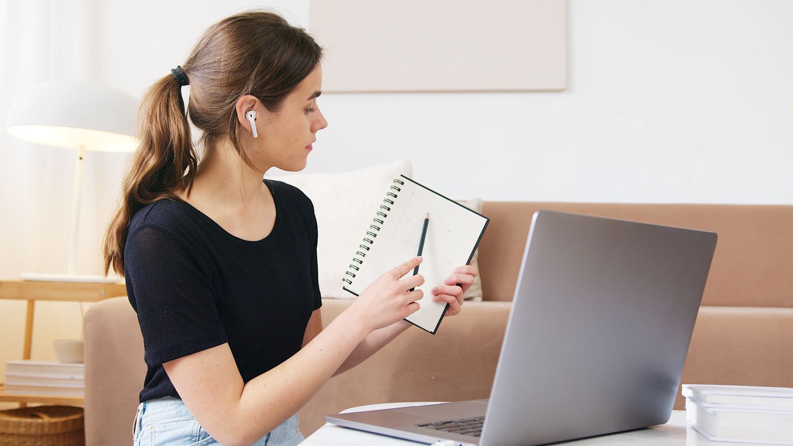 Mitarbeiterin lernt selbstständig am Laptop mit Notizbuch